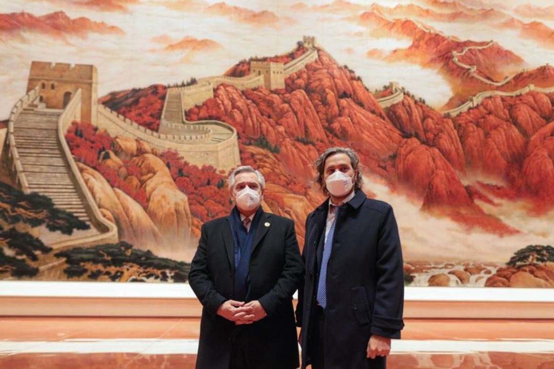 El presidente y Santiago Cafiero posan. Detrás una pintura en colores rojizos pinta toda la pared